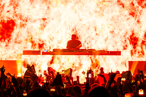 Deorro performing at SILO Dallas with a fiery visual backdrop, energizing the crowd in the futuristic nightclub located in the Design District